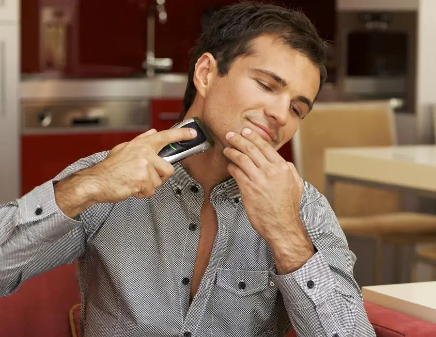 Young man shaving with electric shaver